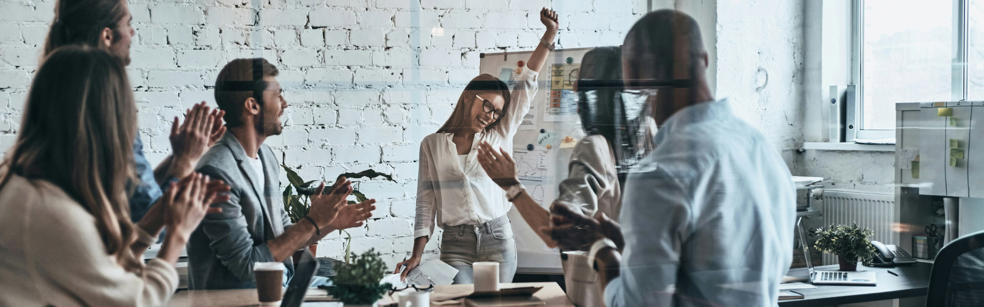 Mitarbeiter im Büro applaudieren ihrer Kollegin